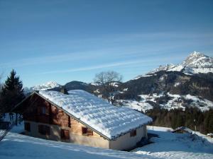 um edifício coberto de neve com montanhas ao fundo em Chalet Crest-Voland, 6 pièces, 8 personnes - FR-1-733-37 em Crest-Voland