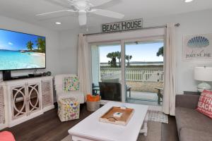 a living room with a tv and a couch and a table at Stay Salty in Saint Joe Beach