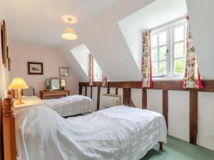 a bedroom with two beds and a window at Oaklawn Cottage in Eye
