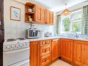 cocina con armarios de madera y horno de fogón blanco en Oaklawn Cottage, en Eye