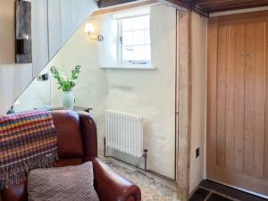 a living room with a leather couch and a window at Cobble Cottage in Instow