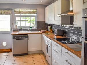 a kitchen with white cabinets and a dishwasher at Chimney Springs in Ormesby Saint Michael