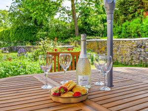 una botella de vino y copas en una mesa de madera en Poplar Farm Cottage en Westbury-sub-Mendip