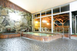 a hot tub in a building with a stone wall at Tango Onsen Hashiudosou in Kyotango