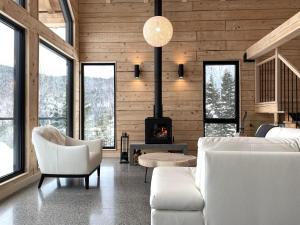 Elle comprend un salon doté d'un mobilier blanc et d'une cheminée. dans l'établissement Le Harfång - Vue spectaculaire sur le Mont Edouard, à LʼAnse-Saint-Jean