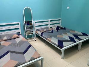 a bedroom with two beds and a blue wall at SS de’ Kelulut Homestay in Marang