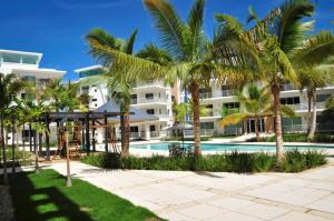 un complejo con piscina y palmeras en Lumina at Jardines Punta Cana Village, en Punta Cana