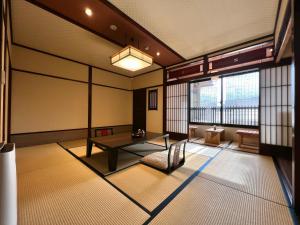 a room with a table and a chair and windows at Ryokan Tanabe in Takayama