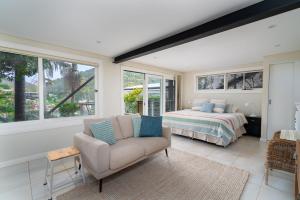 una camera da letto con un letto, un divano e una sedia di Gull Cottage by Beach Stays a Church Point