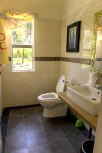 een badkamer met een toilet, een wastafel en een raam bij The Leaf Homestay in Lutong