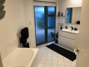 a white bathroom with a tub and a sink at Luxury Waterfront in One Tree Point +15 photos