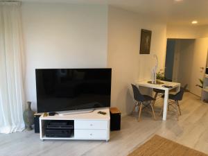 a living room with a large flat screen tv on a white entertainment center at Luxury Waterfront in One Tree Point