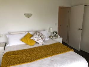 uma cama branca com duas almofadas e um cobertor amarelo em Luxury Waterfront em One Tree Point