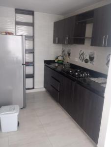 a kitchen with black cabinets and a refrigerator at Apartahotel in Ibagué