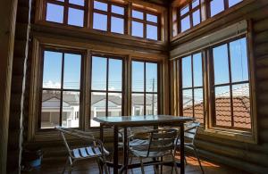 a table and chairs in a room with windows at Log Cabin House in Lutong