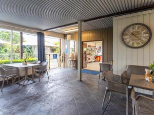 ein Restaurant mit einer Uhr an der Wand sowie Tischen und Stühlen in der Unterkunft NRMA Forster Tuncurry in Tuncurry