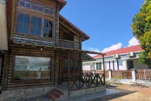 Casa de madera con porche y terraza en Log Cabin House, en Lutong