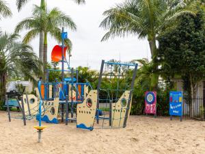 a playground on a sandy beach with palm trees at NRMA Forster Tuncurry in Tuncurry