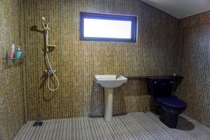a bathroom with a sink and a toilet and a window at Log Cabin House in Lutong