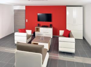 韋尼格羅德的住宿－Pension Schlossidyll，客厅设有红色的墙壁和电视。