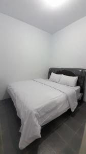 uma grande cama branca com lençóis e almofadas brancos em OYO 92578 Sri Ulina Homestay em Medan