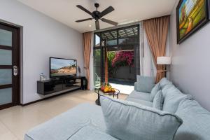 a living room with a blue couch and a tv at VILLA ARUHE | 2 Bedroom Private Pool Villa in Popular Onyx Villas | 3 min to Naiharn Beach in Rawai Beach