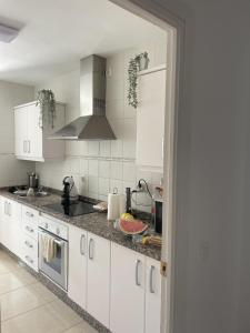 a kitchen with white cabinets and granite counter tops at Remarkable 3-Bed Apartment in Chipiona in Chipiona