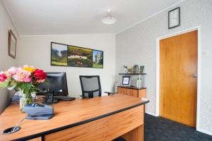 an office with a desk with a computer and a vase of flowers at Tower Road Motel in Matamata