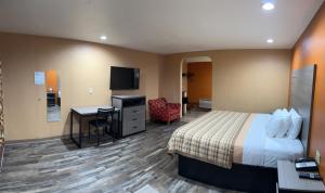 Habitación de hotel con cama, escritorio y TV. en Apex Inn, en Modesto