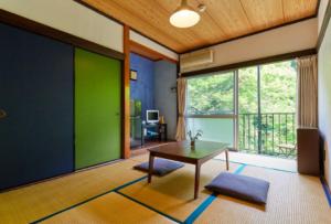 - un salon avec une table et un mur vert dans l'établissement Otsu Nature Garden, à Akiruno
