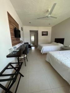 een hotelkamer met 2 bedden, een bureau en een televisie bij Hotel Boutique Luciérnaga in Chiconcuac