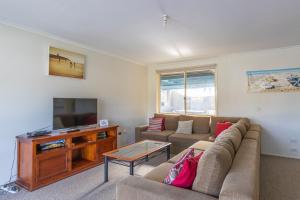 a living room with a couch and a flat screen tv at Peaceful Cul de sac in Sussex Inlet