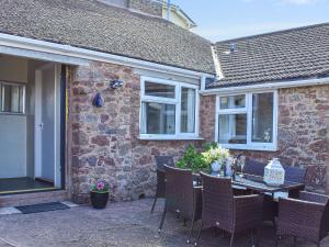 un patio con mesa y sillas frente a un edificio en Thornes Farm Annexe, en West Quantoxhead