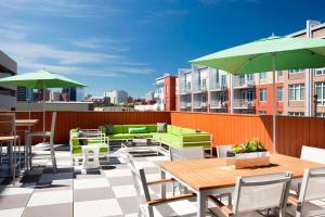 un patio con mesas, sillas y sombrillas verdes en Element Harrison-Newark en Harrison