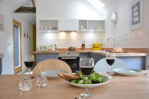 een tafel met een kom salade en twee glazen wijn bij Red Poll Barn in Spexhall