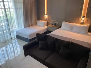 a hotel room with two beds and a couch at Mandarin Eastville, Pattaya - SHA Extra Plus in North Pattaya
