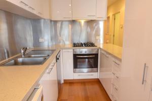 a kitchen with white cabinets and a sink and a stove at Alto Villa 301 in Mount Buller