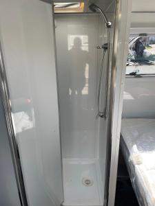 a shower with a glass door next to a bed at Jindabyne caravan hire in Jindabyne