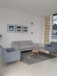 Apartahotel في إباغويه: غرفة معيشة مع أريكة وكرسيين وطاولة