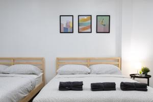 two beds in a white bedroom with three pictures on the wall at P3 Silom Large 2beds full kitchen WIFI 4-6pax in Bangkok