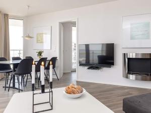 ein Wohnzimmer mit einem TV und einem Tisch mit Stühlen in der Unterkunft Apartment Wendtorf XXVIII in Wendtorf