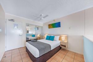 a bedroom with a large bed with blue pillows at Shingley Ocean Views in Airlie Beach +55 photos