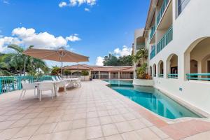 a swimming pool with a table and chairs and an umbrella at Shingley Ocean Views in Airlie Beach
