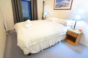a bedroom with a large white bed with a window at Molony's 12 in Mount Buller
