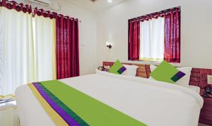 um quarto com uma grande cama branca e cortinas vermelhas em Treebo Trend Infinity View Mahabaleswar em Mahabaleshwar