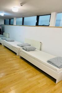 three beds in a room with wooden floors and windows at A.G ROMANA HOSTEL in Bucharest