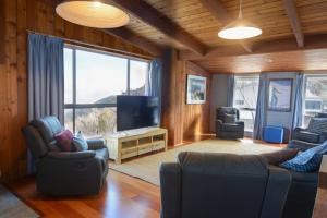 a living room with a couch and a tv andwindows at Moose 10 in Mount Buller