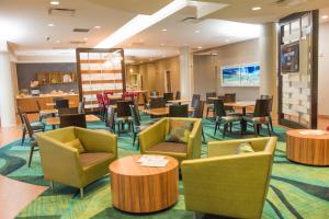 a waiting room with tables and chairs in a hotel at SpringHill Suites by Marriott Buffalo Airport in Williamsville