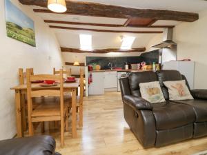 sala de estar con sofá, mesa y cocina en Shepherd's Cottage en Broughton in Furness