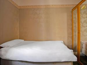 a bed with white sheets and a wooden frame at Great White Horse Hotel in Ipswich